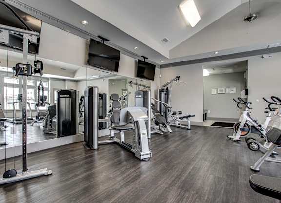 A spacious gym with a variety of equipment including treadmills, stationary bikes, and weight machines. at River Crossing Apartments, St. Charles, MO