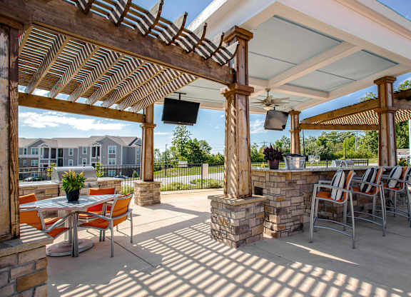 A patio with a table and chairs under a roof. at River Crossing Apartments, St. Charles