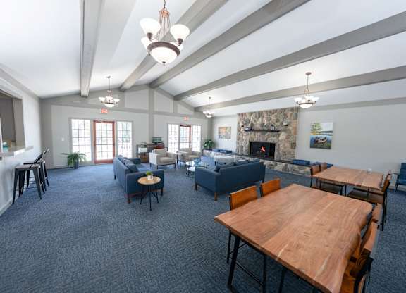 A spacious room with a fireplace and a dining table set up at Rivers Edge Apartments, Waterford, MI