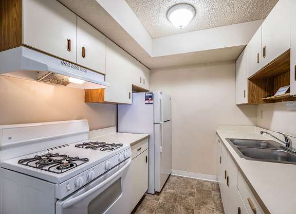A galley-style kitchen with a white stove and refrigerator at Seville Apartments, Michigan