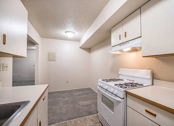 A kitchen with a white stove top oven leading to a dining room at Seville Apartments, Michigan