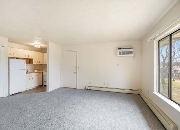 A spacious living room with a carpeted floor and a large window at Seville Apartments, Michigan
