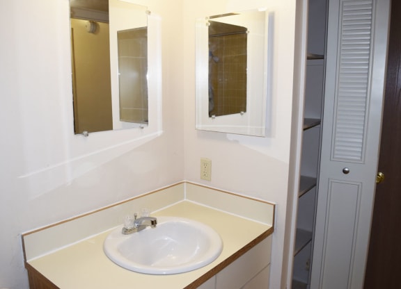 a bathroom with a sink and two mirrors at Seville Apartments in Kalamazoo, MI 49009