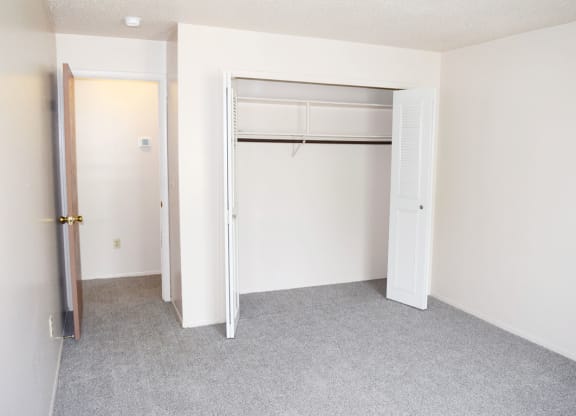 an empty bedroom with a closet and an open door at Seville Apartments in Kalamazoo, MI 49009