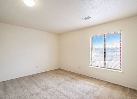 A bedroom with a carpeted floor and a window at Seville Apartments, Kalamazoo, MI