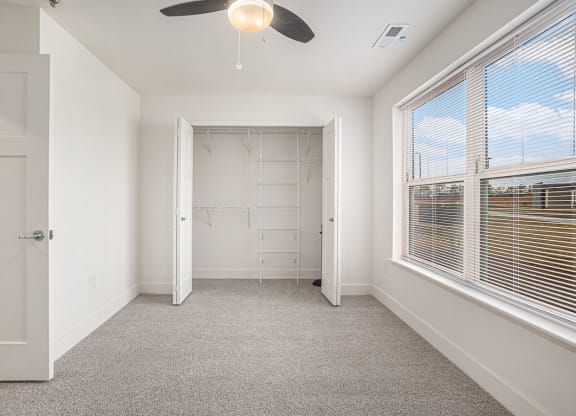 a bedroom with a large window and a walk in closet  at Signature Pointe Apartment Homes, Athens, AL, 35611