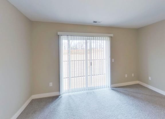 living room with a slider to a balcony end kitchen with a window at Signature Pointe Apartment Homes in Athens, AL