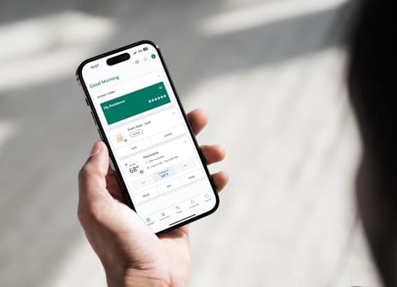 A person is holding a smartphone displaying the SmartRent App
