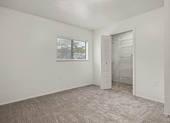 A room with a carpeted floor and a window with blinds.