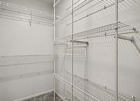 A white walk in closet with shelves and hooks.