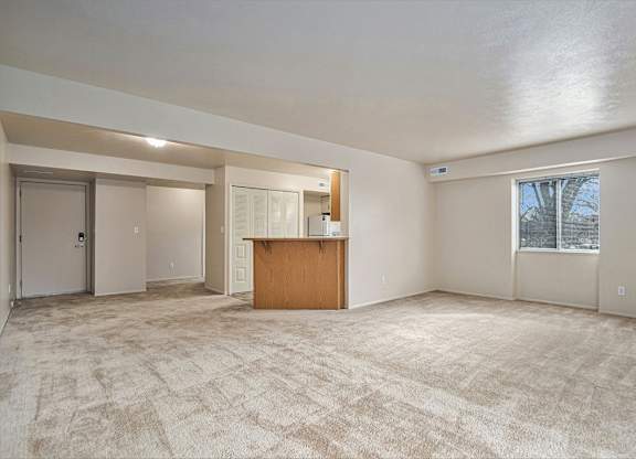 A spacious room with a carpeted floor and a wooden cabinet in the middle.