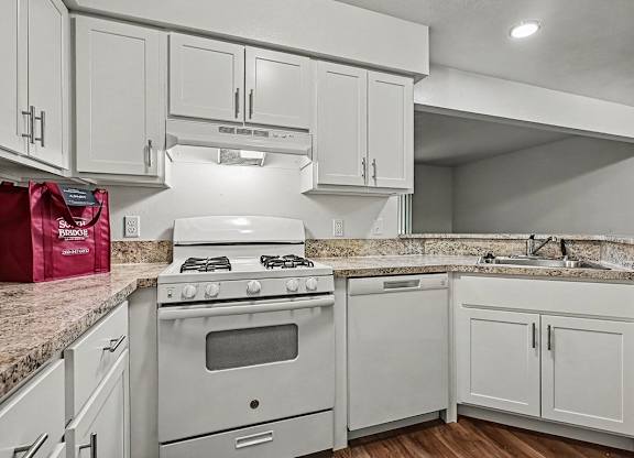 A kitchen with a white stove and cabinets.
