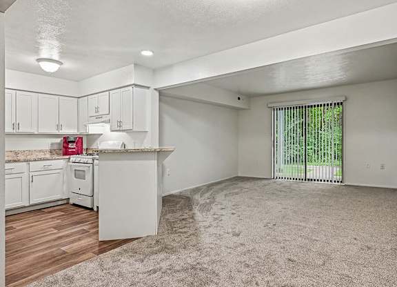 A white kitchen with a window and a carpeted floor.