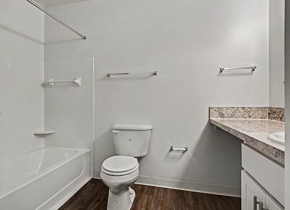 A white toilet sits in a bathroom with a marble counter top.