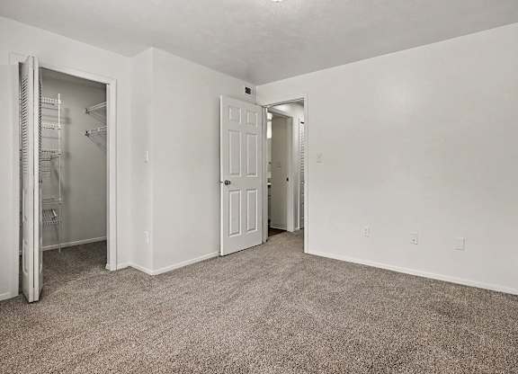 A room with a carpeted floor and two doors.
