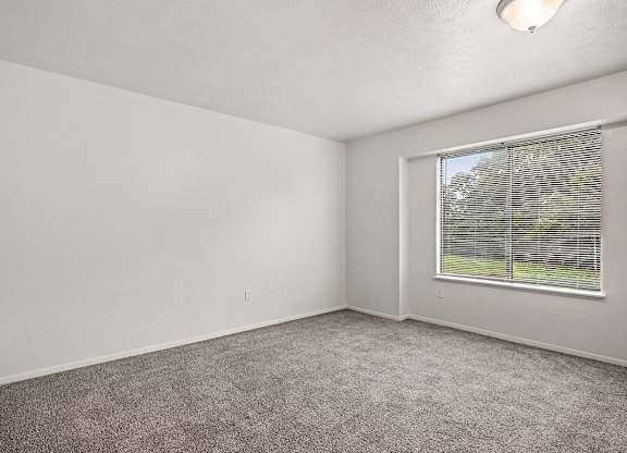 A room with a window and carpeted floor.