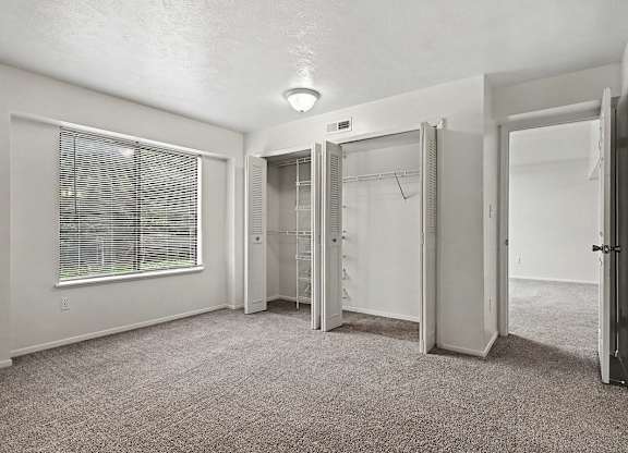 A room with a carpeted floor and a window with blinds.