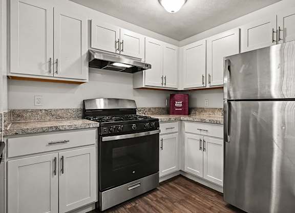 A kitchen with a stainless steel refrigerator, oven, and cabinets.