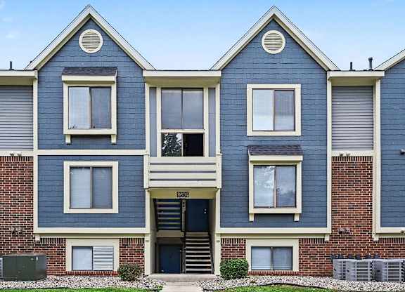 A blue and white two story apartment building with a black door and windows.