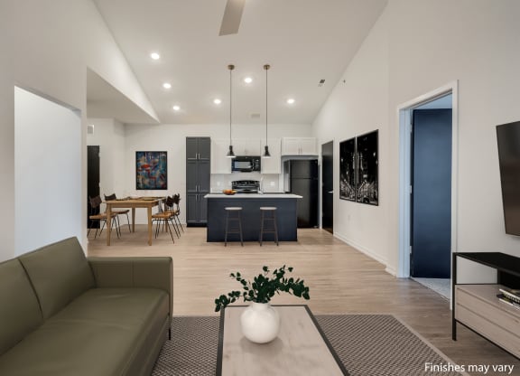 a living room with a couch and a table with chairs in front of a kitchen with a  at Uptown Square Apartments, Michigan, 48083