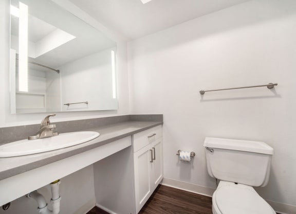 a bathroom with hard surface floors and a mirror at Stoney Pointe Apartment Homes, Wichita