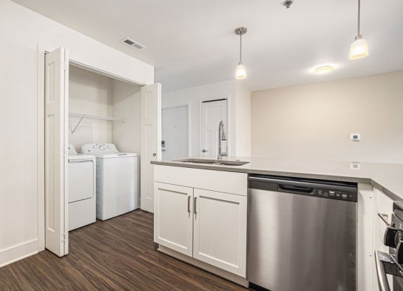 a white kitchen with a stainless steel dishwasher and a washer/dryer at Stoney Pointe Apartment Homes, Kansas