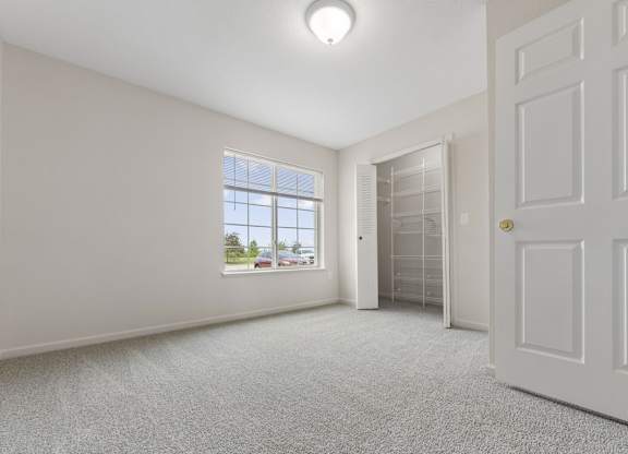 A bedroom with a window and a carpeted floor at Stoney Pointe Apartment Homes, Kansas