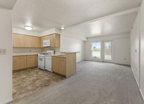 A kitchen with a breakfast bar, white dishwasher and stove top oven at Stoney Pointe Apartment Homes, Wichita
