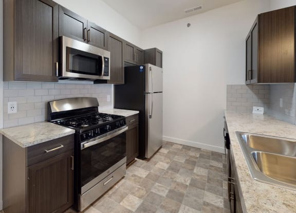 a kitchen with stainless steel appliances and wooden cabinets at Strathmore Apartment Homes, West Des Moines, 50266