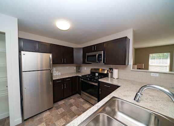 A kitchen with stainless steel appliances and a pantry at Strathmore Apartment Homes, West Des Moines, IA