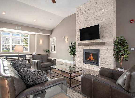A community room with a fireplace and a television at Strathmore Apartment Homes, West Des Moines, IA