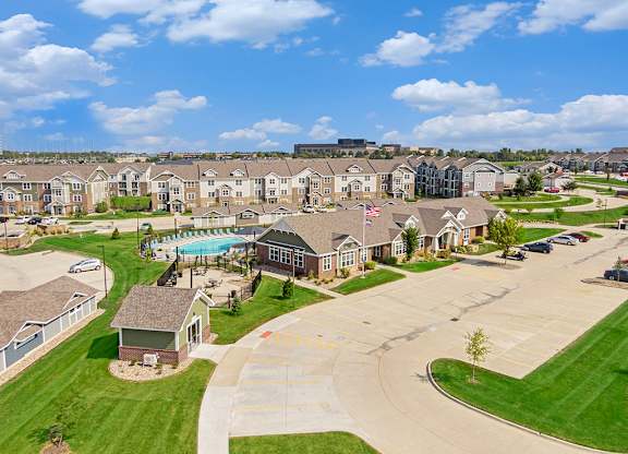 A large apartment community with a swimming pool and a flag flying in the breeze at Strathmore Apartment Homes, Iowa