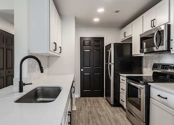 A modern kitchen with black and white appliances and cabinets. at Sundance Apartments, Indianapolis, 46237