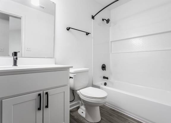 A white bathroom with a toilet, sink, and bathtub. at Sundance Apartments, Indianapolis
