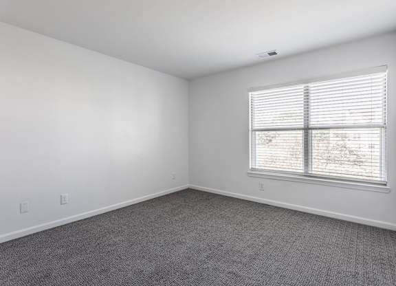 A room with a window and a carpeted floor. at Sundance Apartments, Indianapolis