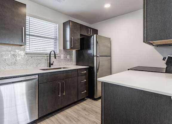 A modern kitchen with dark wood cabinets and stainless steel appliances. at Sundance Apartments, Indiana, 46237