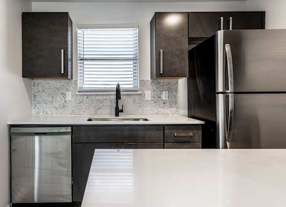 A modern kitchen with a stainless steel refrigerator and a marble backsplash. at Sundance Apartments, Indianapolis, IN, 46237