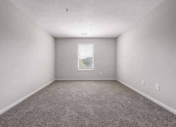 A room with a carpeted floor and a window with blinds. at Sunscape Apartments, Virginia