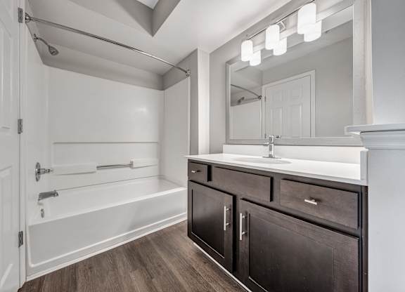 A bathroom with a white tub, sink, and mirror. at Sunscape Apartments, Virginia