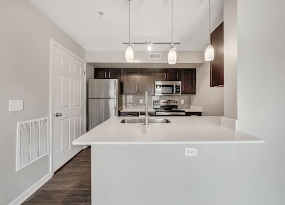 A modern kitchen with a white island and stainless steel appliances. at Sunscape Apartments, Roanoke