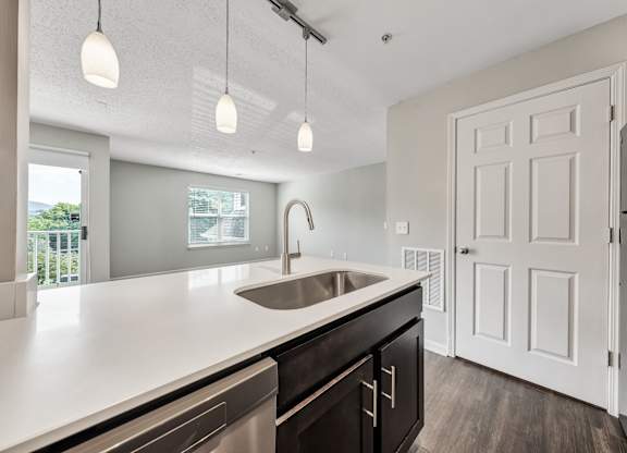 A modern kitchen with a white countertop and a stainless steel sink. at Sunscape Apartments, Virginia