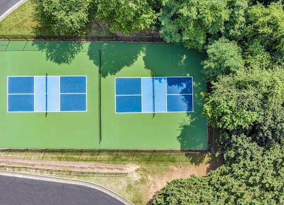 Two tennis courts surrounded by trees. at Sunscape Apartments, Virginia