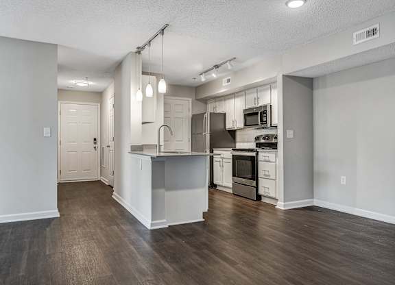 A kitchen with white cabinets and a wooden floor. at Sunscape Apartments, Virginia