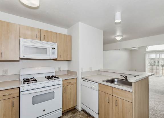 A kitchen with white appliances and wooden cabinets at Tall Oaks Apartment Homes, Kalamazoo, 49009