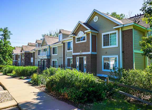 An exterior apartment building with green bushes in front at Tall Oaks Apartment Homes, Kalamazoo, MI, 49009