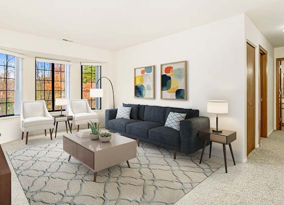 A living room with bay windows and grey couch at Tanglewood Apartments, Oak Creek