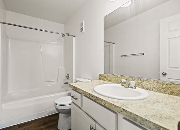 A white bathroom with a sink, toilet, and bathtub at Tanglewood Apartments, Oak Creek, WI