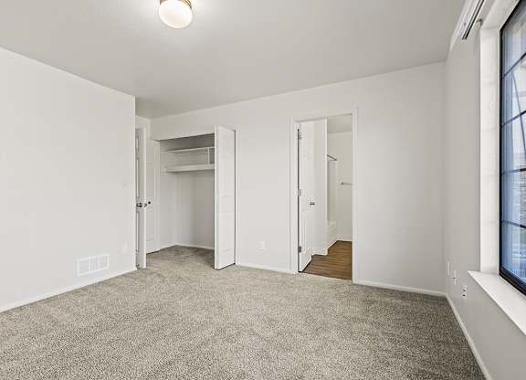 A bedroom with a carpeted floor and white walls at Tanglewood Apartments, Oak Creek, WI