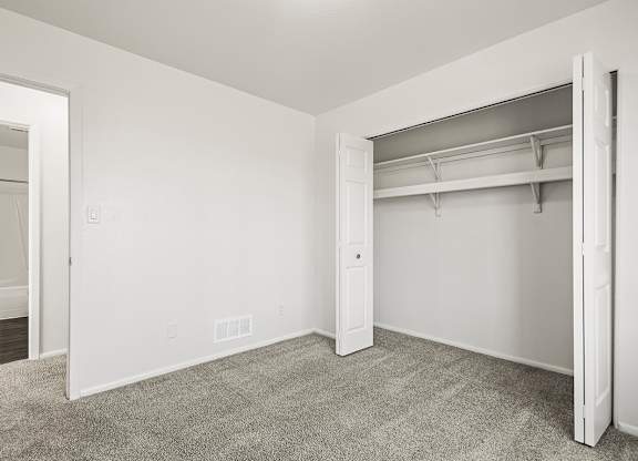 A white bedroom with a closet and carpeted floor at Tanglewood Apartments, Oak Creek, WI