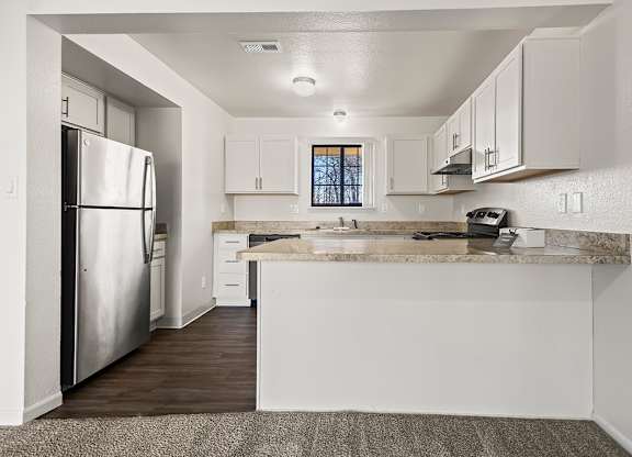 A kitchen with a stainless steel refrigerator, window, and white cabinets at Tanglewood Apartments, Oak Creek, WI